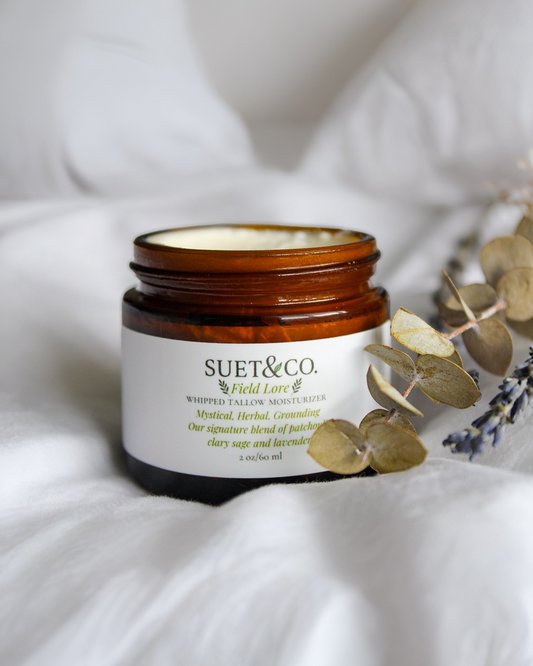 Jar of Suet & Co. product Field Lore on a white surface with eucalyptus leaves.