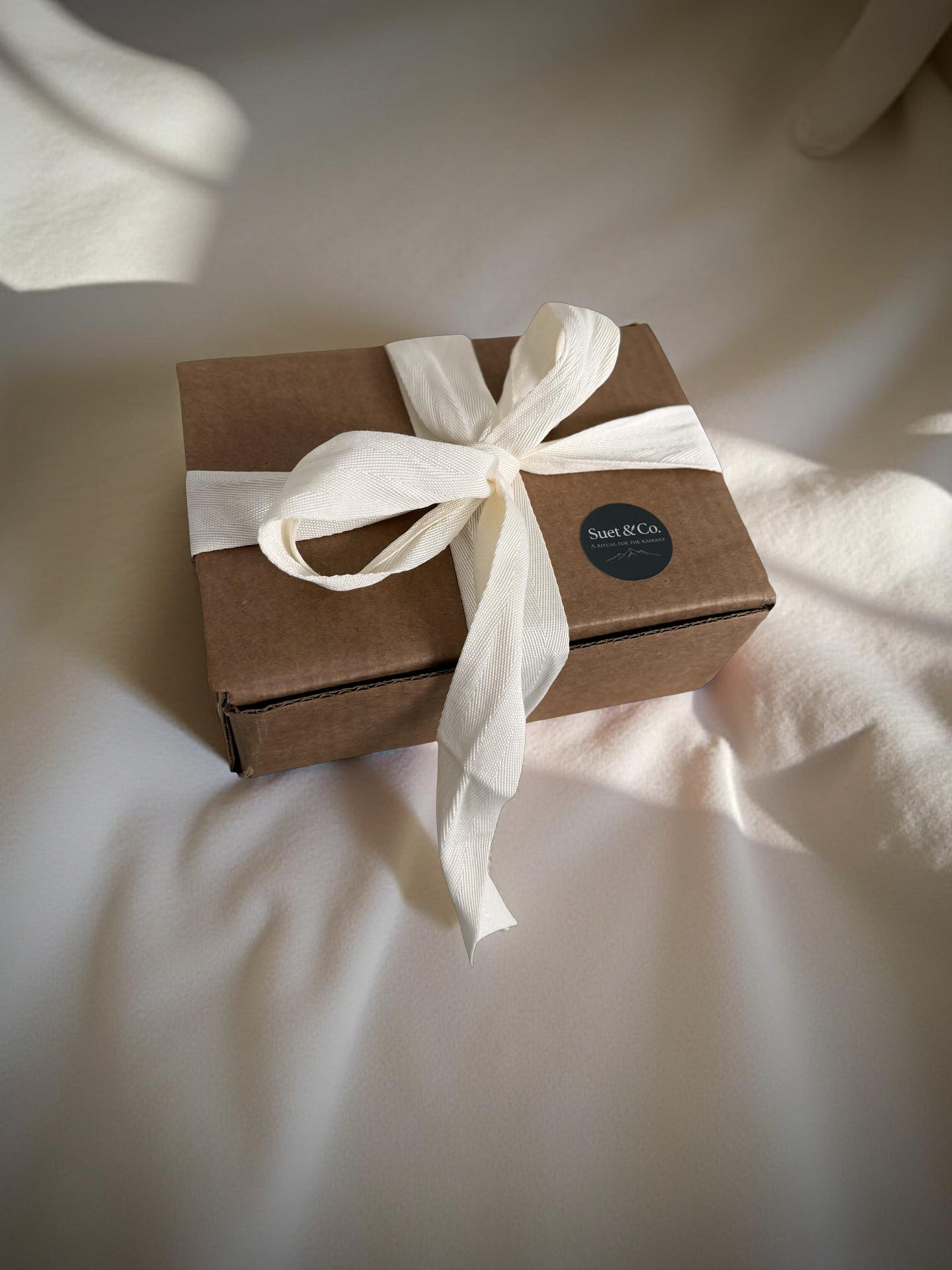 Brown gift box with a white ribbon on a soft fabric background